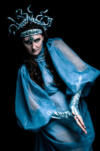 A gloomy portrait of a woman in makeup and a night witch costume on a dark background