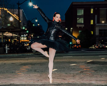 Woman ballet dancing on city street at night