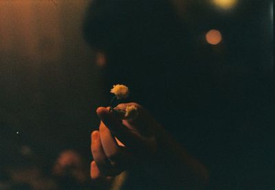 Close-up of hand holding cigarette at night