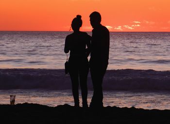 Silhouette people looking at sea against sky during sunset