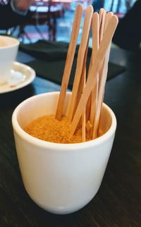 Close-up of brown sugar and wooden sticks in a paper cup for being served with coffee 