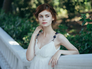 Portrait of young woman standing against blurred background