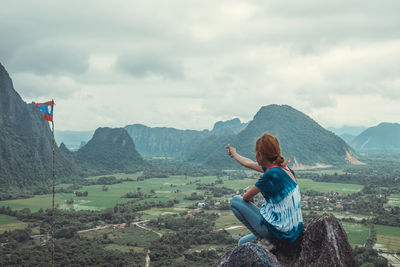 Side view of mid adult woman pointing at flag against mountains