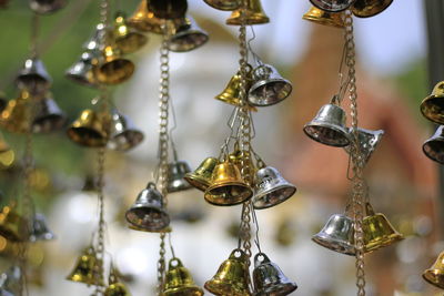 Close-up of small bells hanging against buddha statue