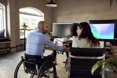 Business colleagues discussing while sitting at desk in office