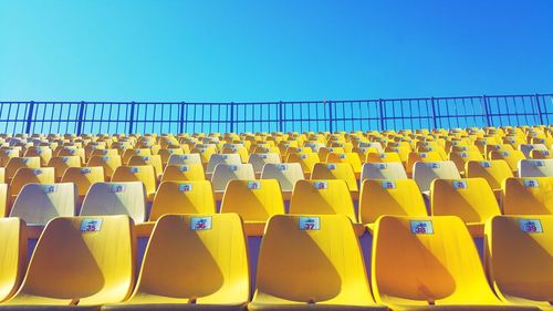 Empty chairs against clear blue sky