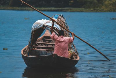 Rear view of fisherman boating on lake