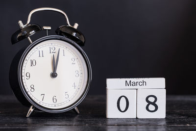 Close-up of clock with calendar on wooden table