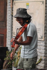 Young mucisian standing and playing violin.