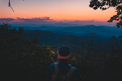 Rear view of man looking at mountains during sunset