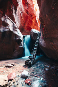 Long exposure of waterfall flowing down rock steps in narrow canyon