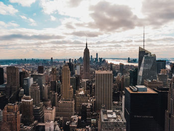 Aerial view of city buildings against cloudy sky