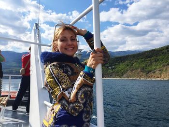 Portrait of smiling young woman in boat on river against sky