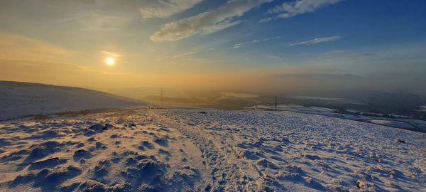 Scenic view of snow covered land against sky during sunset