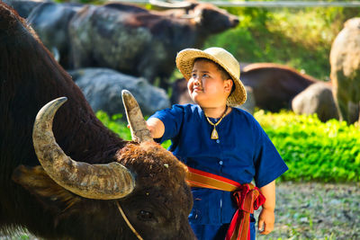 Cute boy with buffalo standing outdoors