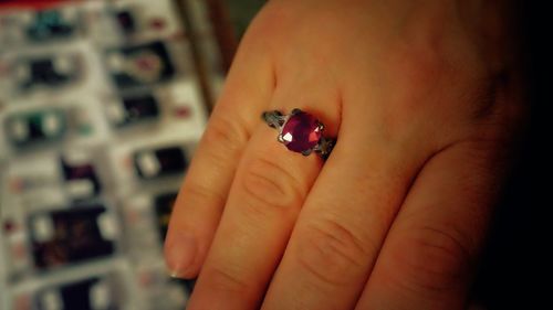 Cropped image of woman with red ruby ring on finger