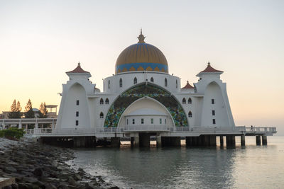 Mosque over sea against sky during sunset