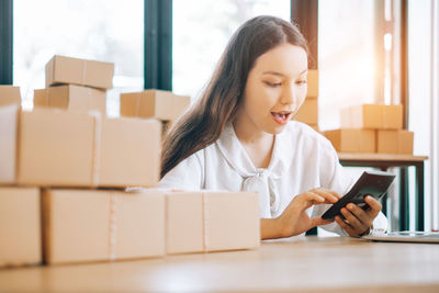 Young woman using mobile phone in box