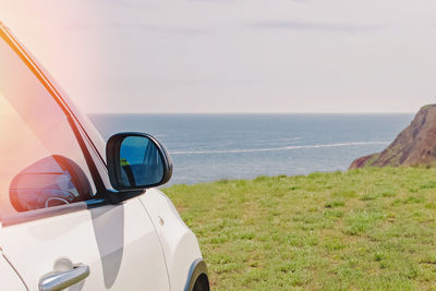 White car standing near the seaside , close-up shot of rear view mirror