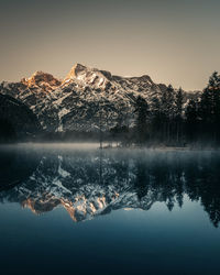 Scenic view of lake by snowcapped mountains against sky during winter