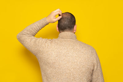 Rear view of woman against yellow background