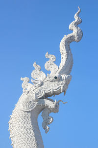 Low angle view of dragon statue against clear blue sky