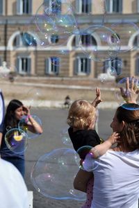 People standing amidst bubbles in city