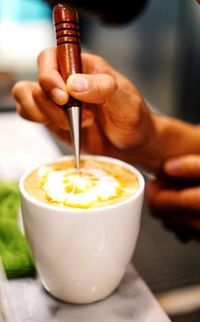 Close-up of hand pouring coffee in cup