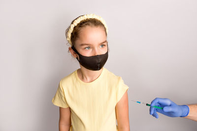 Portrait of a girl holding yellow flower against white background