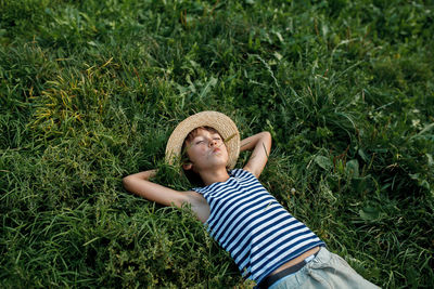 Teenage boy making face while lying on grass outdoors