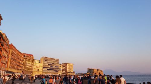 Group of people in front of buildings against clear sky