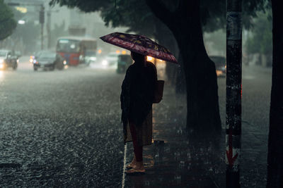 Rear view of person walking on wet street during rainy season