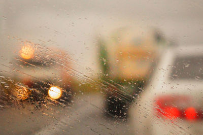 Cars on road seen through wet car windshield during rainy season