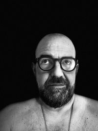 Portrait of man wearing eyeglasses against black background