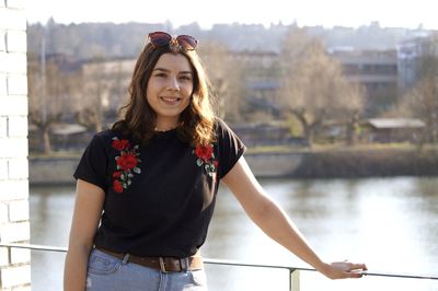 Portrait of smiling young woman standing against built structure