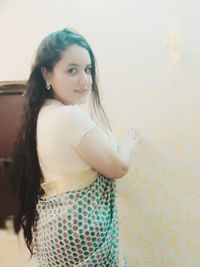 Portrait of young woman standing against wall