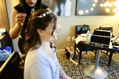 Midsection of beautician styling woman hair in salon