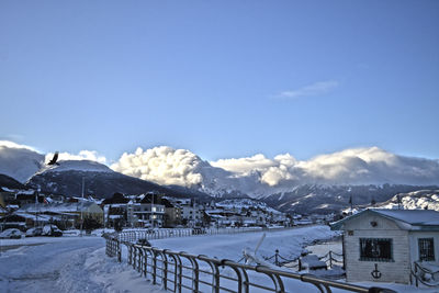 Snow covered houses and mountains against sky