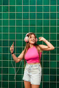 Portrait of young woman standing against wall