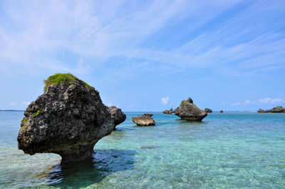 Rocks in sea against blue sky