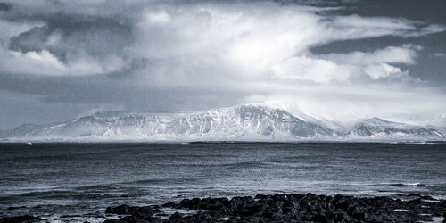 Scenic view of sea and snowcapped mountains against sky