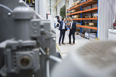 Two businessmen talking in factory shop floor