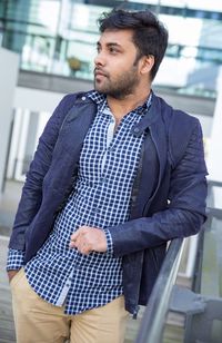 Young man looking away while standing in balcony