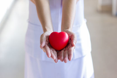 Midsection of nurse holding heart shape