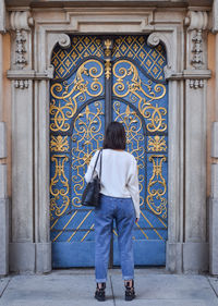 Rear view of man standing against closed door of building