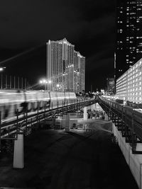 Illuminated modern buildings in city against sky at night