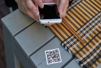 From above of crop unrecognizable male using smartphone and scanning qr code of menu of restaurant