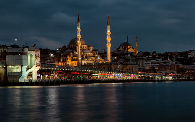 Strait by buildings and mosques against cloudy sky