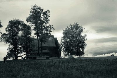 Trees on field against cloudy sky