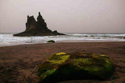 Rocks on beach against clear sky